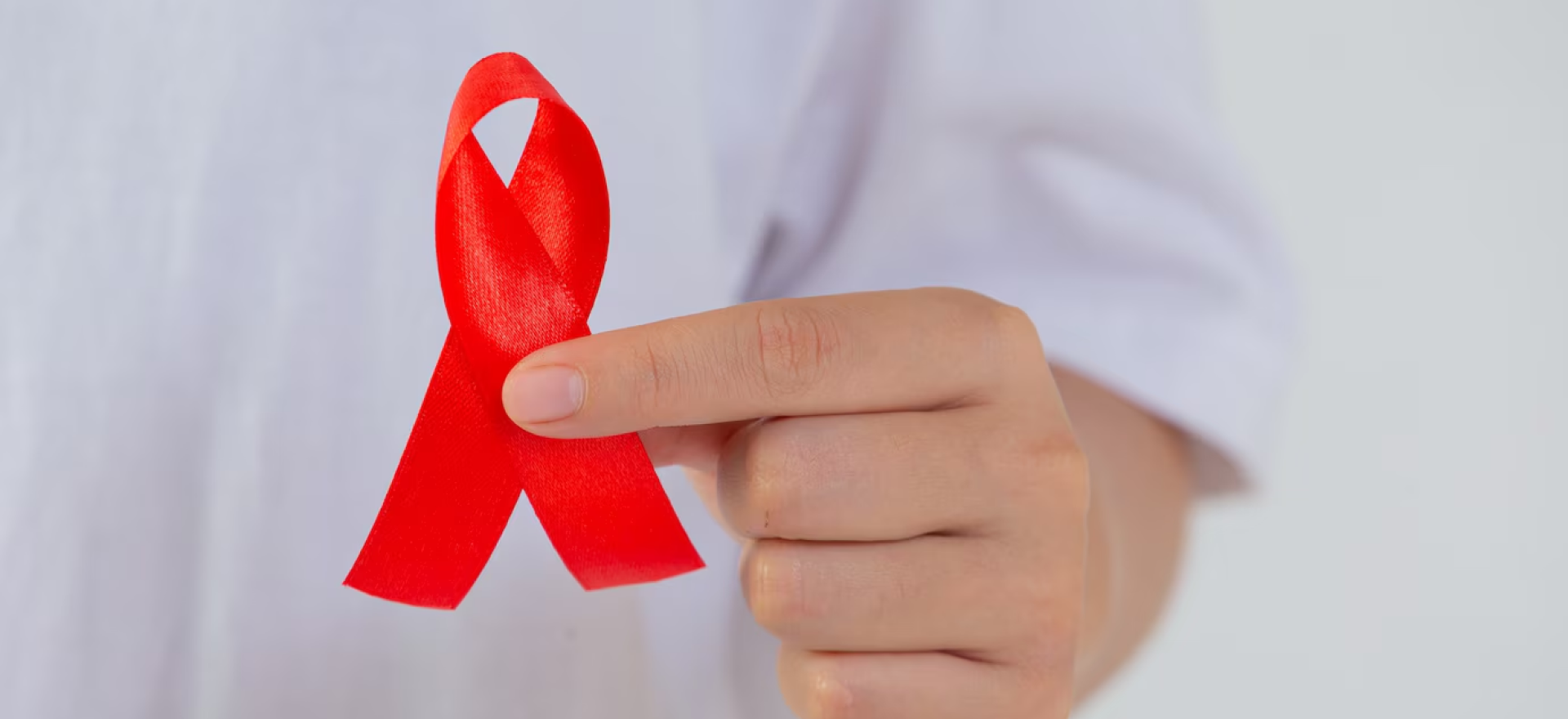 Hand holding a red ribbon symbolizing cancer awareness for oncology and cancer procedures