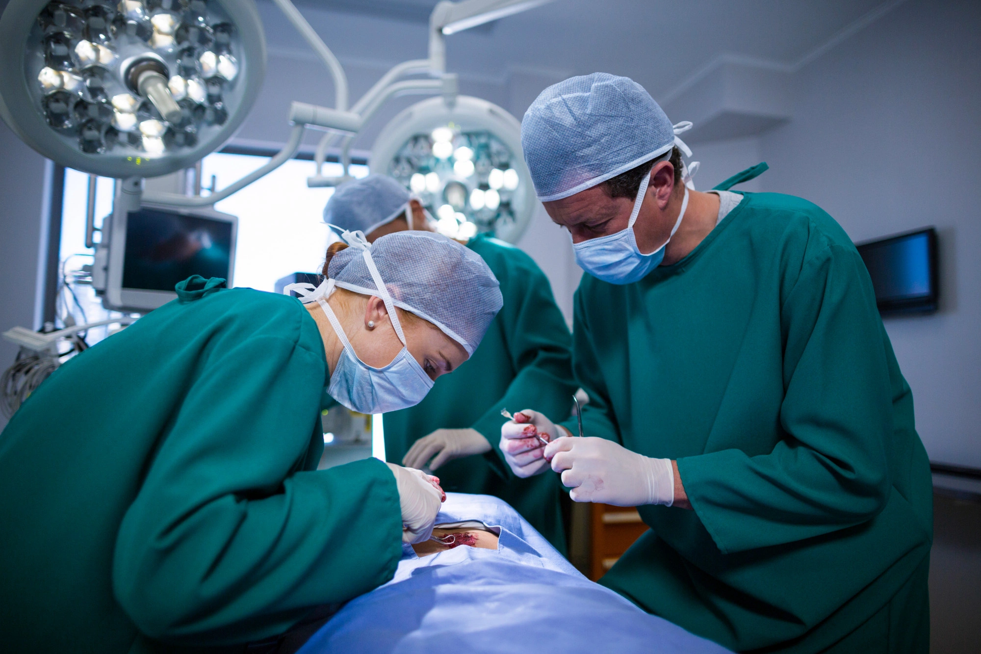 Surgeons performing an operation in a sterile operating room under bright surgical lights