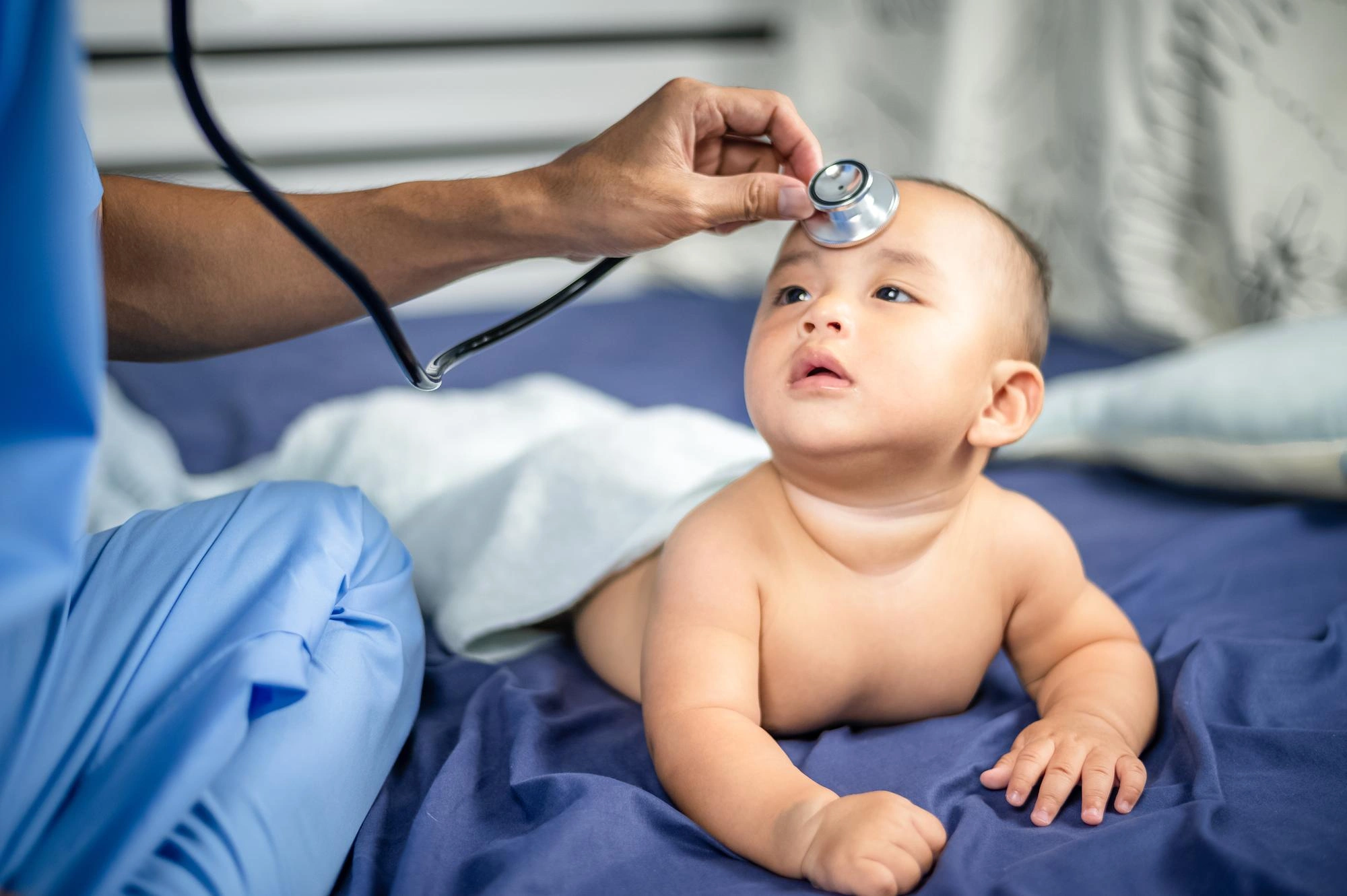 Pediatrician using a stethoscope to check a happy baby during a medical examination